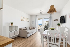Un soggiorno moderno con divano, tavolo da pranzo e sedie, una ventola a soffitto e vista all'esterno.