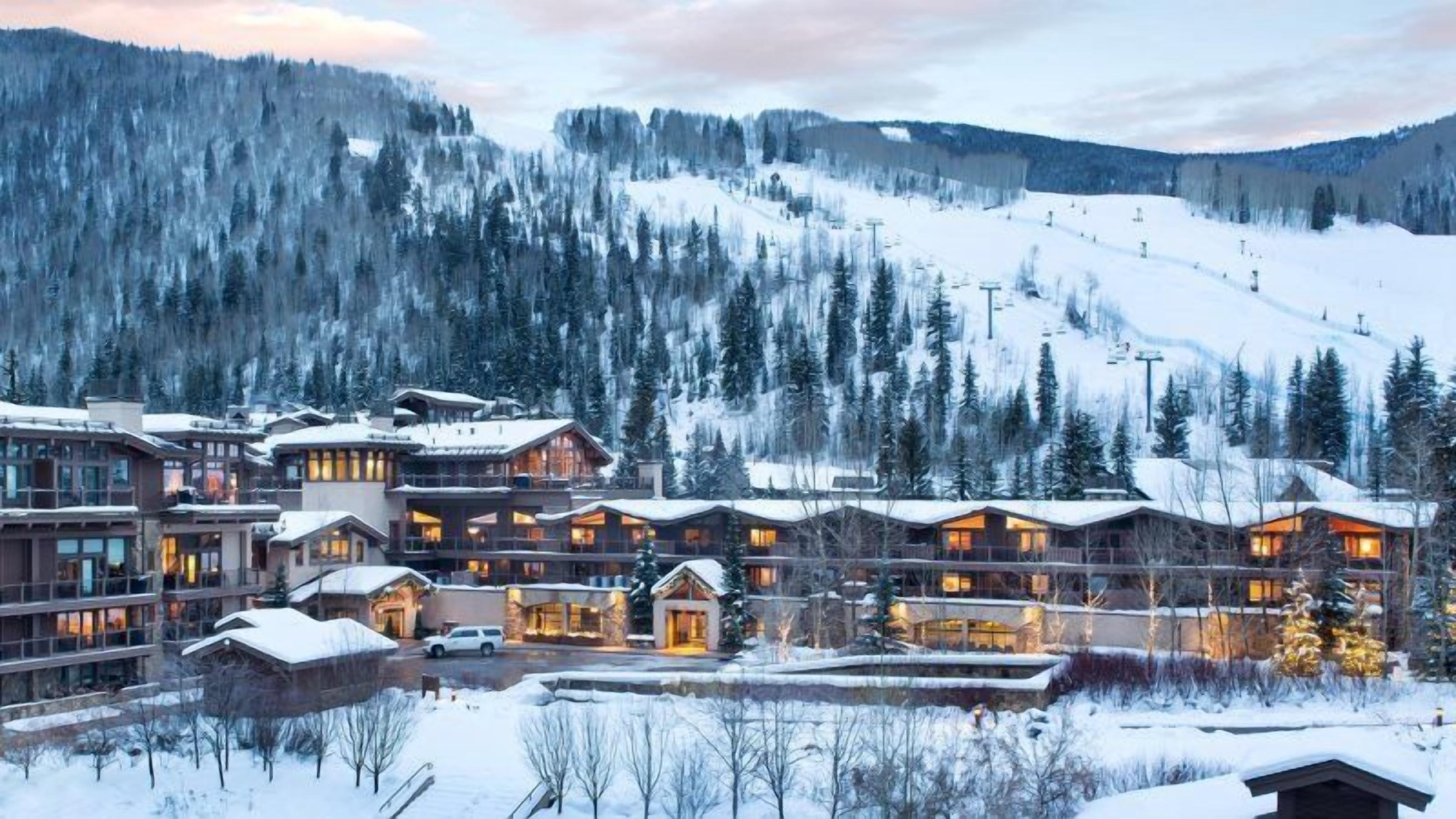 Un lodge innevato con diversi edifici, impianti di risalita e montagne sullo sfondo.