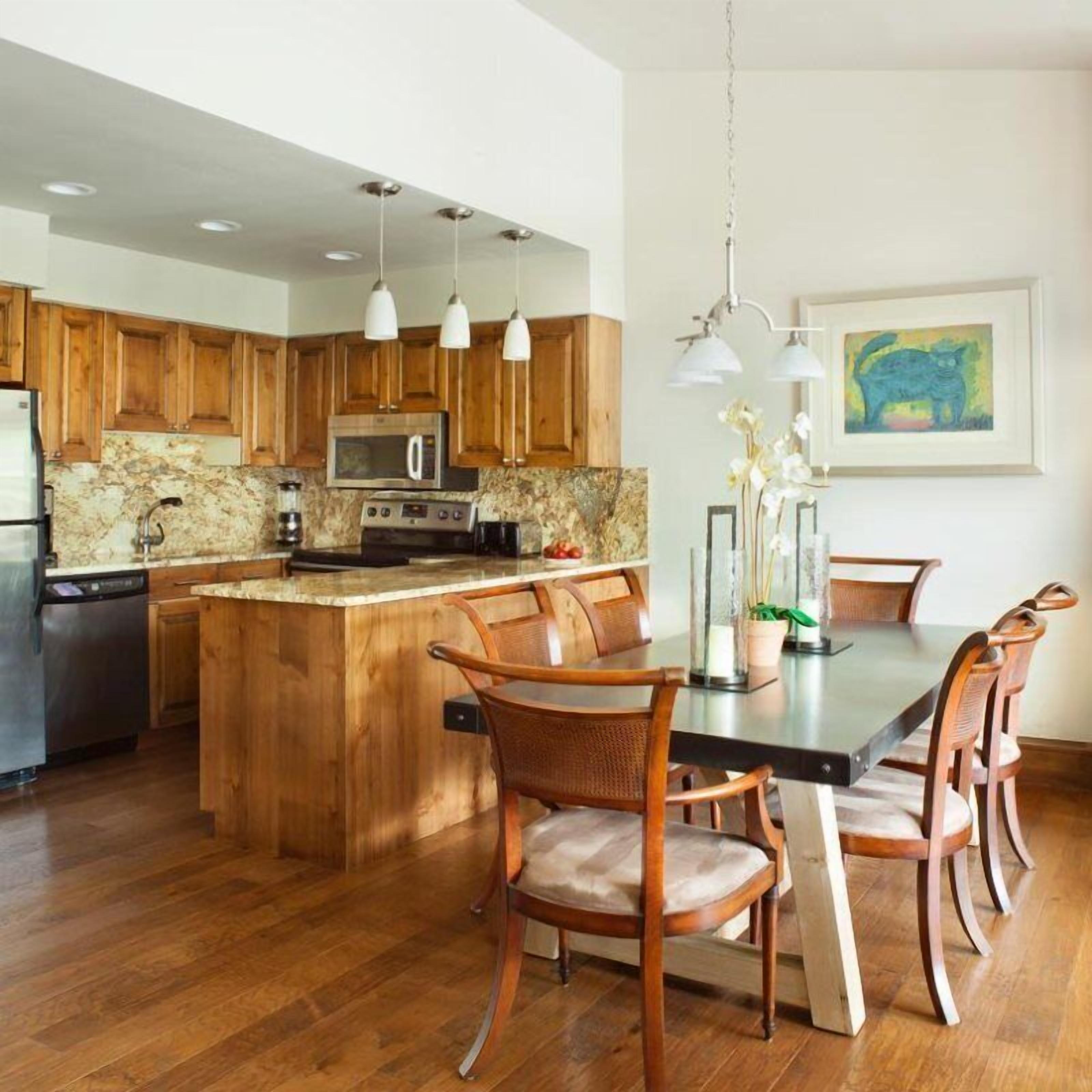 Une cuisine moderne avec des meubles en bois, un îlot central et un coin repas comprenant une table et des chaises.