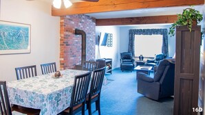 Un coin repas avec une table et des chaises, un mur en briques, un ventilateur de plafond, et un salon avec un canapé et un fauteuil.