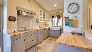 A modern kitchen with grey cabinets, wooden countertops, and a large wall clock. - 'Roadrunner Roost' at Rams Hill Golf Resort! (Borrego Springs)