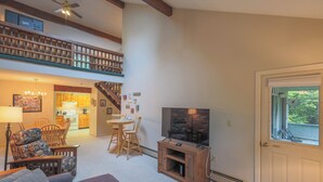 Un amplio salón con una mesa de comedor, sillas, un sofá, un televisor y una escalera que sube a un nivel superior.
