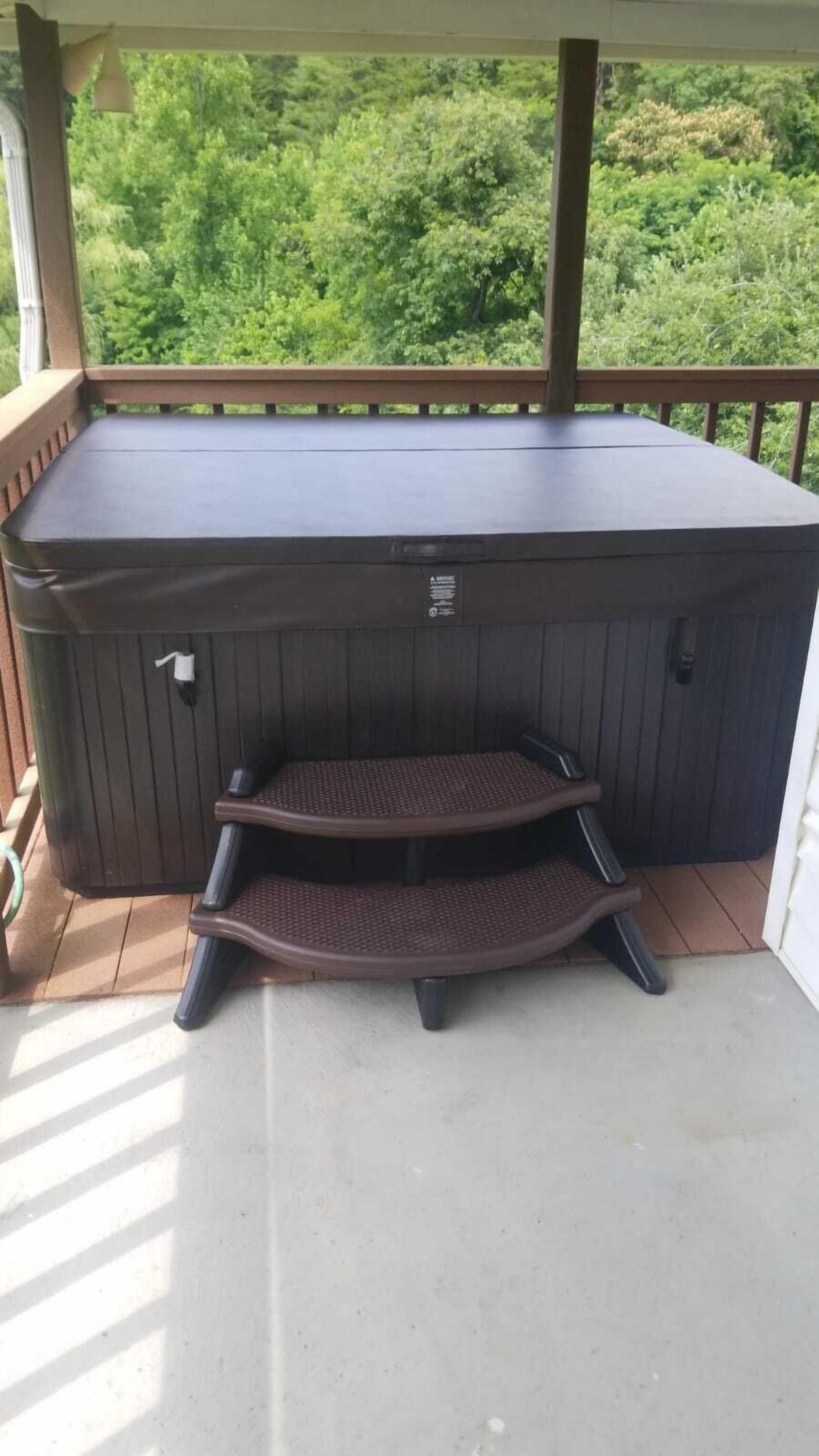 Un jacuzzi con terraza de madera y vista a la vegetación.