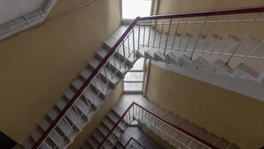 Interior de diversos nivells amb una escala central, un fanal i un arranjament floral a la part inferior.