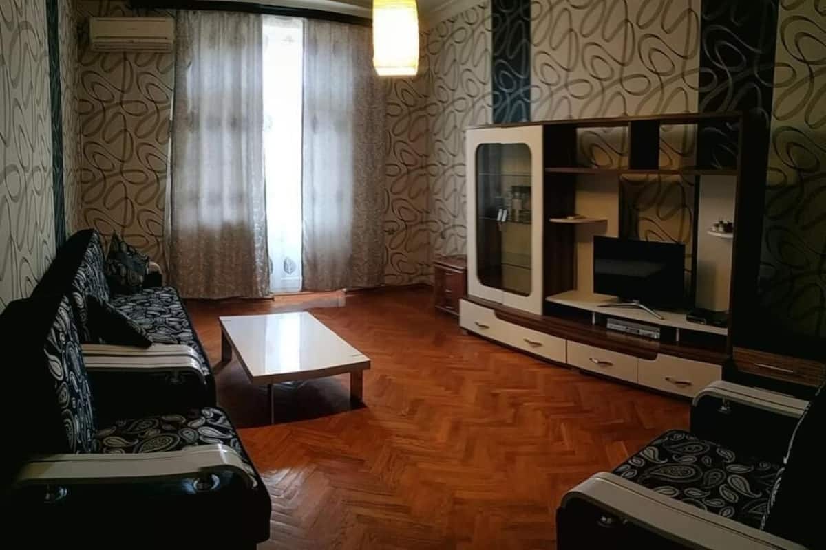 A living room with patterned wallpaper, a sofa, a coffee table, and a TV stand.