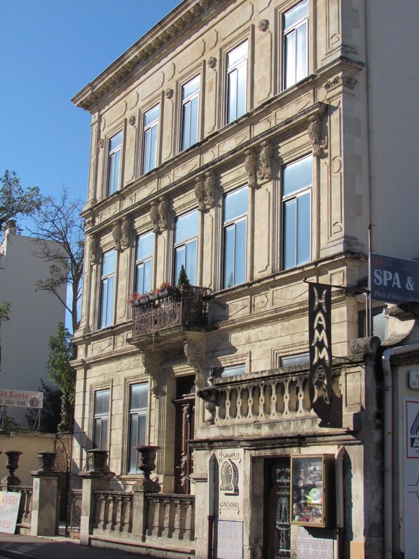 A historic building with ornate architectural details, including a balcony with decorative railings and a sign indicating a spa and restaurant.