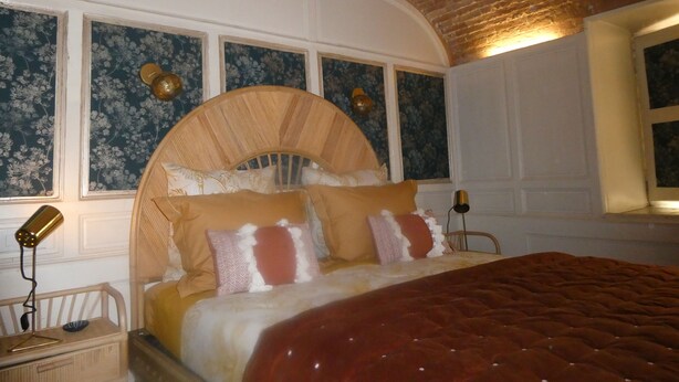 Una camera da letto con un letto grande, due lampade ai comodini, una testiera in legno e carta da parati a motivi floreali.