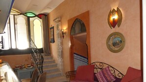 Un soggiorno accogliente con divano, poltrone, una scala e una zona pranzo con tavolo e sedie.