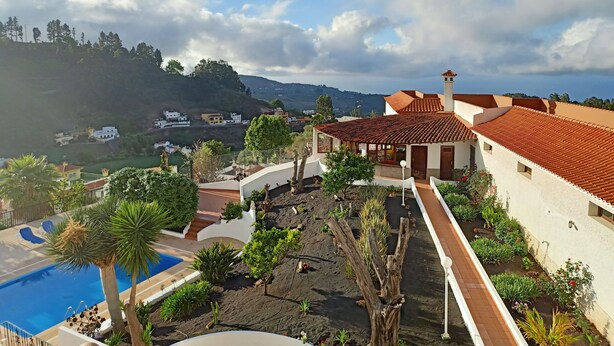 Un complexe hôtelier doté d’une piscine, de jardins aménagés en terrasses et offrant une vue sur les collines environnantes.