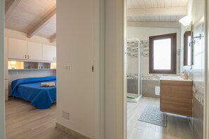 Un dormitorio con cama, un baño con ducha y una kitchenette.