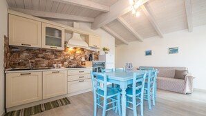Une cuisine avec un mur recouvert de pierres, des armoires en bois, une table à manger avec des chaises et un canapé.