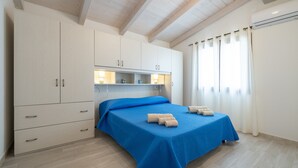 Une chambre à coucher avec un lit, une armoire, un miroir et une fenêtre avec des rideaux.
