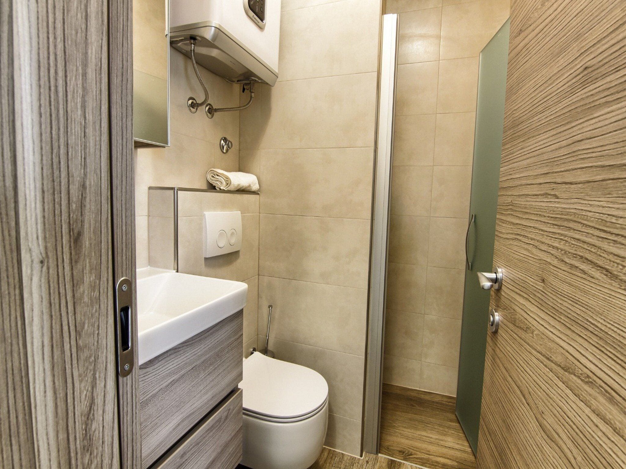 A bathroom with a toilet, a sink, a towel rack, and a shower.