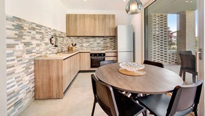 A modern kitchen with a central island, wooden cabinets, and a dining area with a round table and chairs.