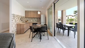 A modern kitchen with a dining area, large windows, and a sliding glass door leading to an outdoor patio.