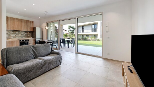 A modern living room with a sofa, a TV, and a dining area with chairs and a table.
