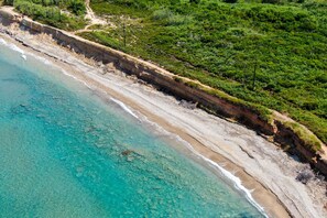 An aerial view of a coastal area with a sandy beach, a rocky cliff, and dense greenery. - Pavlos & Sofia Harmony Villa – Private Pool with Sea View, Garden, Terrace & Wi-Fi (Corfu)