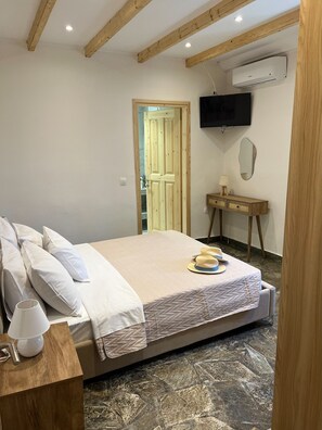 A bedroom with a bed, bedside table, lamp, and a TV mounted on the wall.