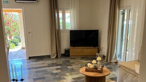 Olohuone, jossa on sohva, televisio, sohvapöytä ja takka.