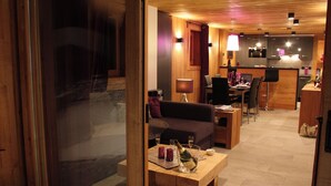 A modern interior with a wooden floor, a sofa, a dining table, and a kitchen area.