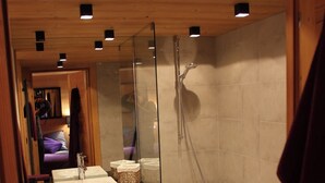 A modern bathroom with wooden cabinetry, a glass shower enclosure, and a white bathtub.
