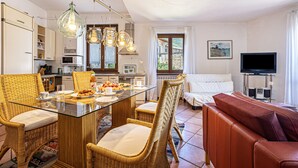 Een moderne keuken met een eethoek, rieten meubels, een bank en een televisie.