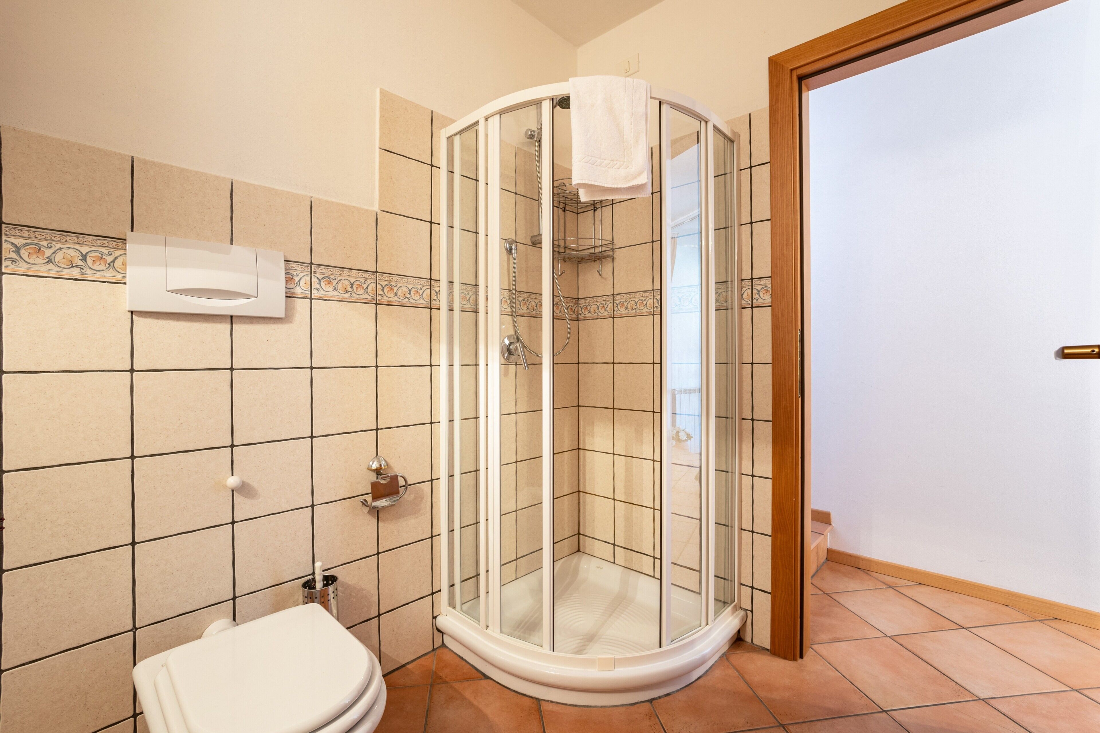 Et badeværelse med brusekabine i glas, toilet og håndklædetørrer.