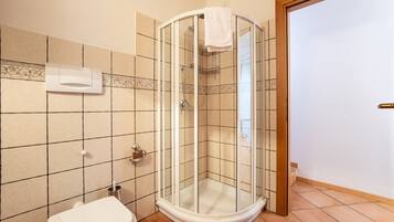 Et badeværelse med brusekabine i glas, toilet og håndklædetørrer.