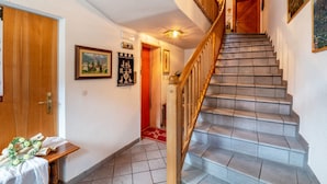 Una scala con ringhiere in legno e un tappeto rosso che conduce a una porta.