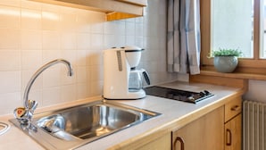 Una cucina moderna con lavello in acciaio inossidabile, macchina del caffè e pensili in legno.