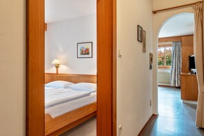 A bedroom with a wooden bed, a bedside lamp, and a framed picture on the wall.