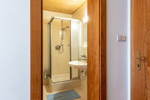 Une salle de bain avec une douche à parois de verre, un lavabo et une porte en bois.