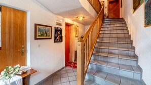 Una escalera con barandillas de madera, una puerta roja y un cuadro colgado en la pared.