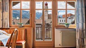 Una habitación con un banco de madera, una mesa y una vista de la montaña a través de una ventana con marco de madera.