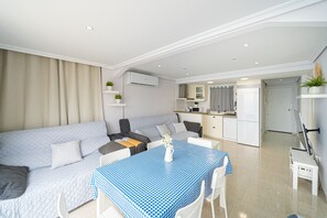 Un salon moderne comprenant un canapé, une table à manger avec des chaises, un coin cuisine et une porte donnant sur une autre pièce.