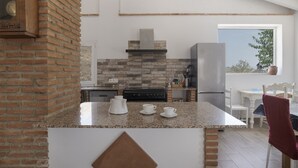 A kitchen with a brick wall, granite countertop, and modern appliances. - Finca El Porvenir with Mountain View, Pool, Whirlpool, Wi-Fi & Garden (El Gastor)