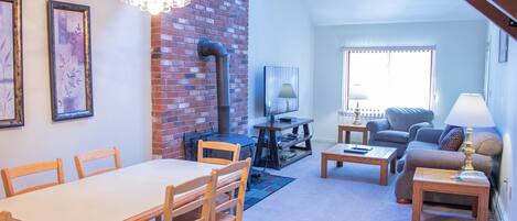 A living room with a dining table, chairs, a sofa, a TV, and a fireplace.