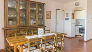 Ein Essbereich mit Holztisch und Stühlen, einer Schrank mit Glastüren, einer weißen Tür und einer Küche mit Herd und Backofen.