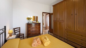 Ein Zimmer mit einem Bett, einem Holzschrank, einem Schminktisch und einem Stuhl.