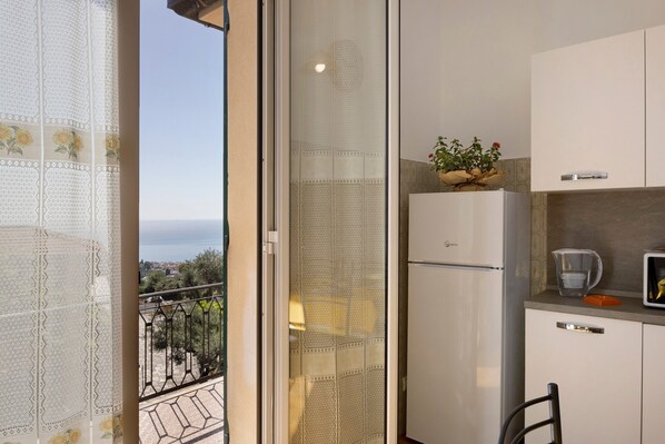 Un balcon avec vue, une cuisine équipée d’un réfrigérateur et un coin repas avec une chaise.