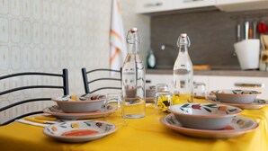 Ein Esstisch mit Tellern, Schüsseln und einer Flasche, drapiert mit einer gelben Tischdecke.