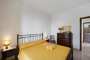 Une chambre à coucher comprenant un lit, une table de chevet avec une lampe, une commode, une chaise et un miroir.