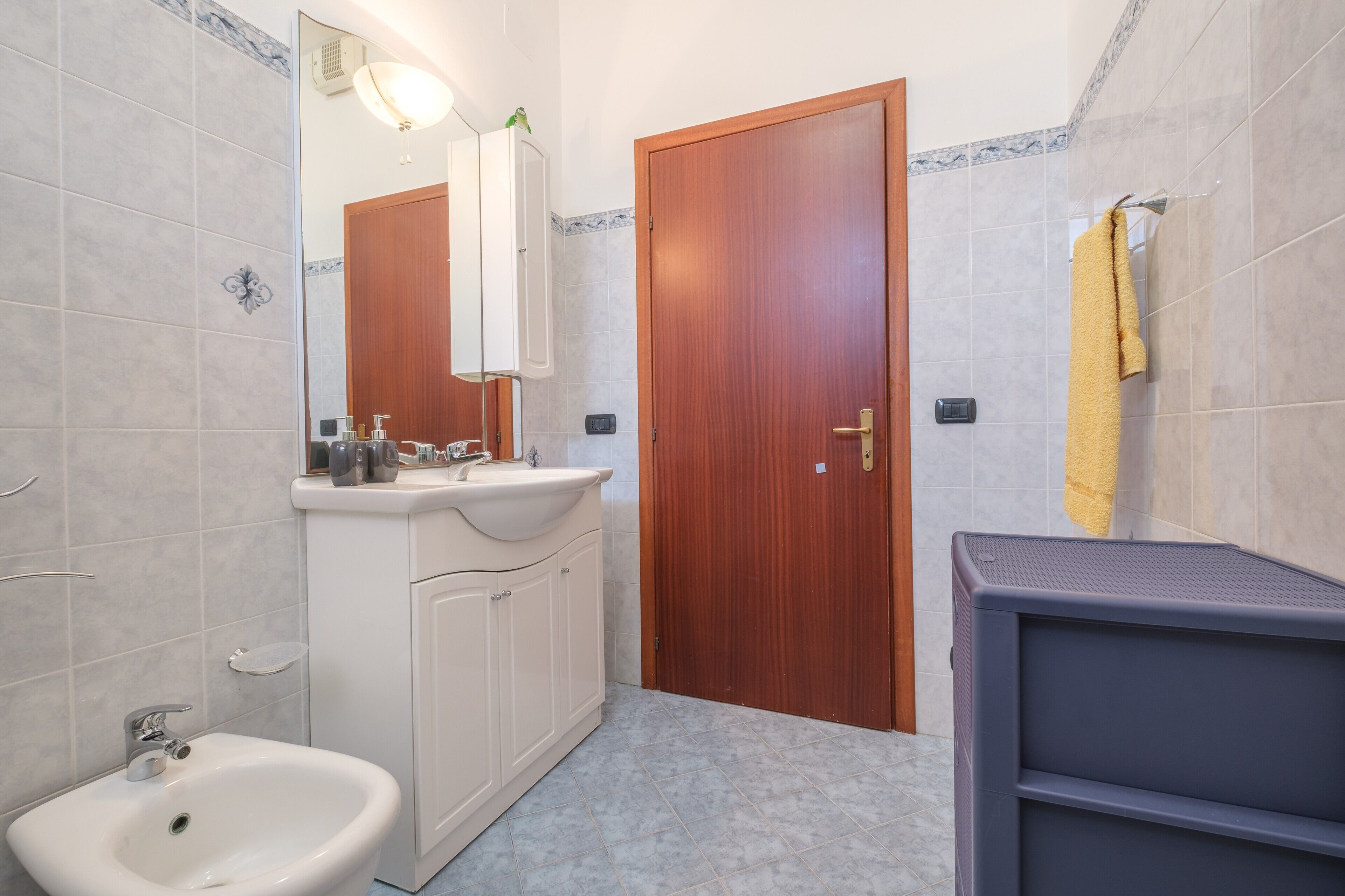 Ein Badezimmer mit Waschbecken, Spiegel und Holztür.