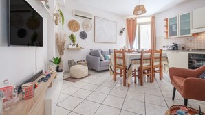 A modern kitchen with a dining area, a flat-screen TV mounted on the wall, and a window with curtains. - Holiday Home 'La Marchese' close to the Beach with Terrace & Wi-Fi (Oliveri)