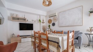 A dining area with a table set for four, wooden chairs, a television, and wall decorations. - Holiday Home 'La Marchese' close to the Beach with Terrace & Wi-Fi (Oliveri)