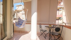 A balcony with a hanging chair, a table with chairs, and a view of neighboring buildings. - Holiday Home 'La Marchese' close to the Beach with Terrace & Wi-Fi (Oliveri)