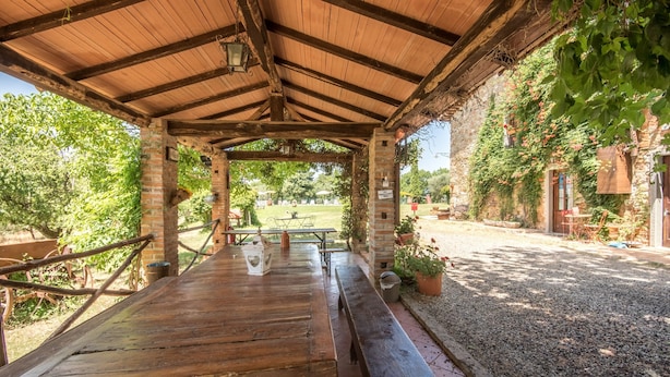 An outdoor wooden pavilion with a brick wall, a picnic table, and potted plants. - Apartment "Trilocale Etrusco" with Shared Pool, Garden & Wi-Fi (Castiglion Fibocchi)