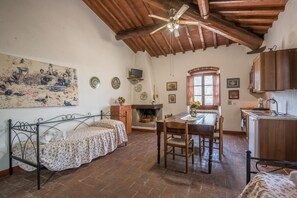 Una habitación rústica con cama, una mesa de comedor, chimenea y una zona de cocina.