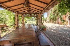 Un pavillon extérieur en bois, doté d’un mur en briques, d’une table de pique-nique et de plantes en pot.
