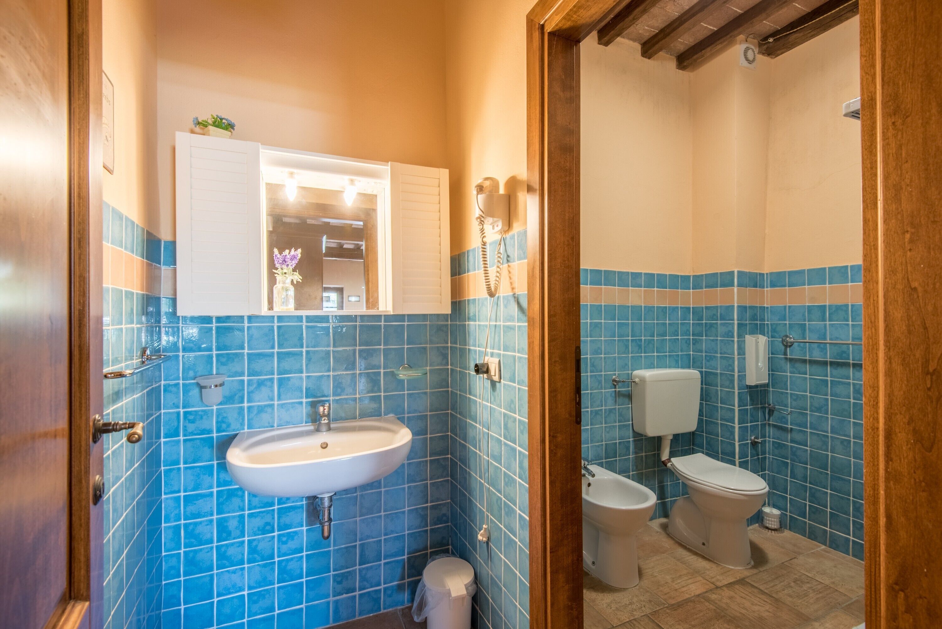 Un baño con azulejos azules, un lavamanos, un inodoro y un bidé.